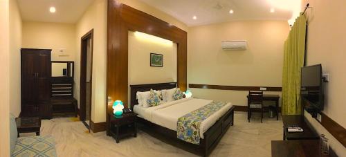 Dormitorio con cama, escritorio y TV en The Birder's Inn, en Bharatpur