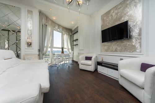una camera bianca con un letto e una TV a parete di Exquisite panoramic views apartment Dnipro embankment a Kiev