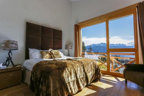 a bedroom with a large bed and a large window at Crans Luxury Lodges in Crans-Montana