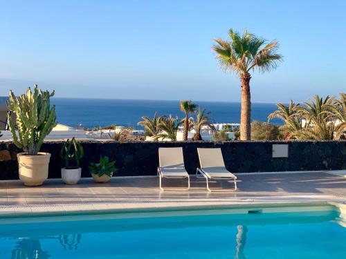 two chairs by a swimming pool with the ocean in the background at Villa Dois Mares Puerto Calero in Puerto Calero