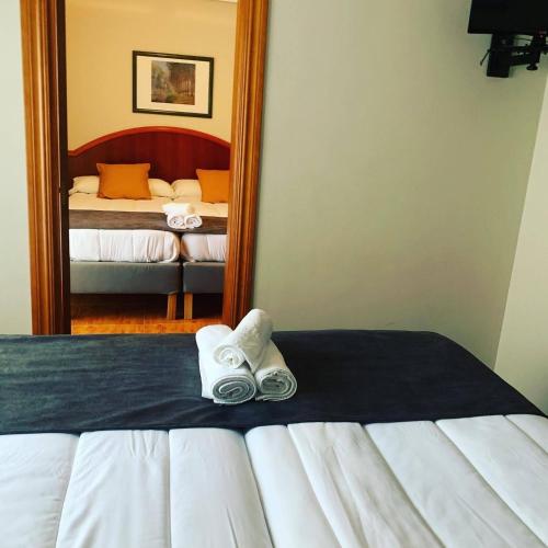 a bedroom with a bed with a mirror and two slippers at Hotel - Apartamentos Peña Santa in Onís