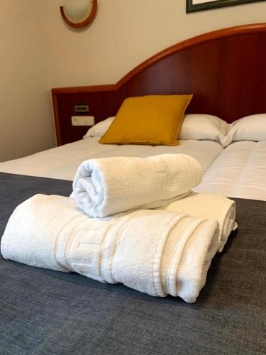 two white towels sitting on top of two beds at Hotel - Apartamentos Peña Santa in Onís