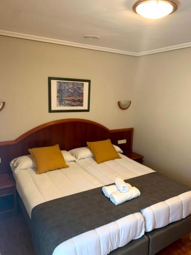 a bedroom with a large bed with two towels on it at Hotel - Apartamentos Peña Santa in Onís