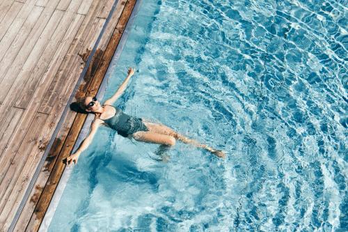 a woman swimming in a swimming pool at Boutique Hotel Das Rivus in Leogang