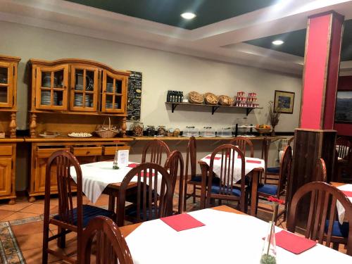 a restaurant with tables and chairs and a kitchen at Hotel - Apartamentos Peña Santa in Onís