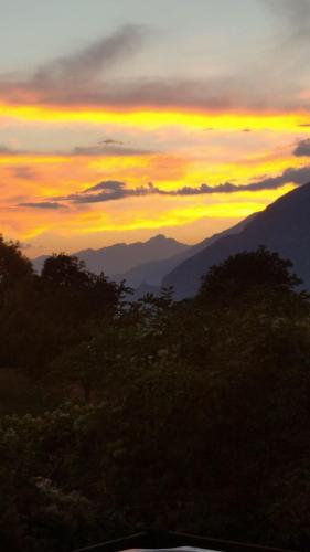 a sunset in the mountains with trees in the foreground at il Battito in Saint Vincent