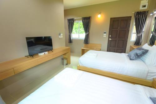 a bedroom with two beds and a flat screen tv at Avarin Resort in Pak Chong