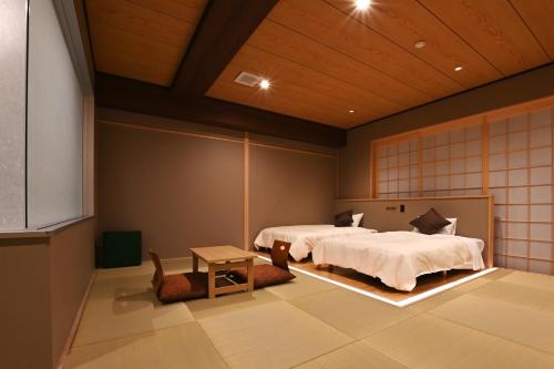 a room with two beds and a table in it at 原鶴の舞 in Asakura