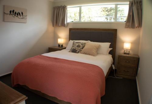 ein Schlafzimmer mit einem Bett mit zwei Nachttischen und einem Fenster in der Unterkunft Roselle Farm Cottage in Portobello