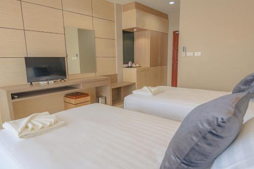 a hotel room with two beds and a flat screen tv at Avarin Resort in Pak Chong