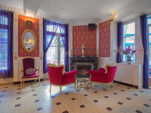 a living room with red chairs and a fireplace at Petit Château in Laborde