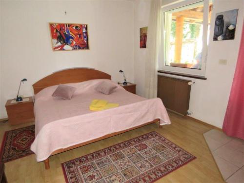 una camera da letto con un letto con una coperta rosa e una finestra di Apartma Jager a Bovec