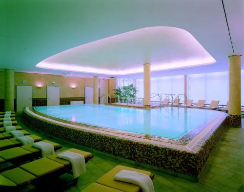 a large swimming pool in a hotel with chairs at Residenz am Dom Boardinghouse Apartments in Cologne
