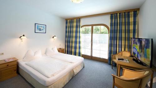 a hotel room with a bed and a window at Ferienhotel Alpenhof in Aurach bei Kitzbuhel
