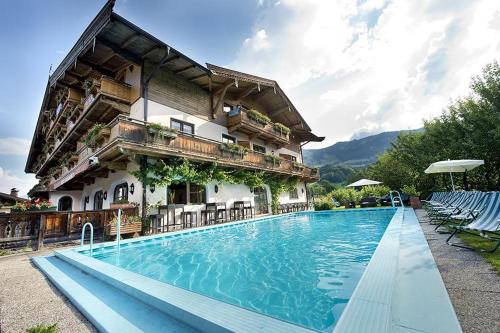 a hotel with a swimming pool in front of a building at Ferienhotel Alpenhof in Aurach bei Kitzbuhel