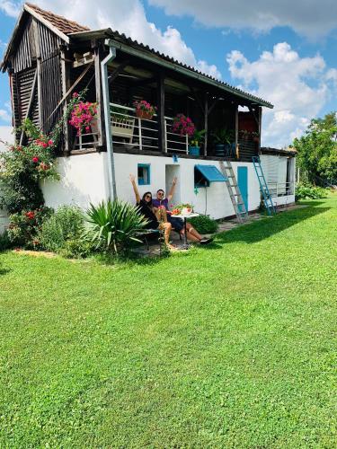 two people sitting on a bench in front of a house at Lux House Olga in Ruma