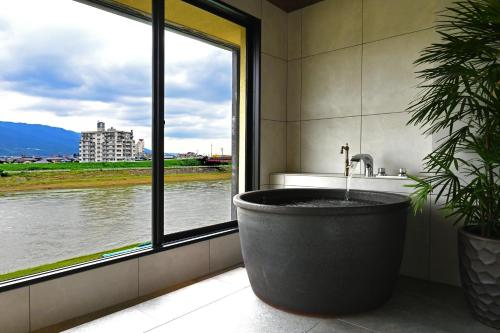 a bathroom with a bath tub in front of a window at 原鶴の舞 in Asakura
