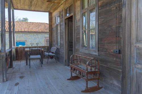 a porch with a bench and a table and chairs at Ethno Sazano Hotel in Sazano