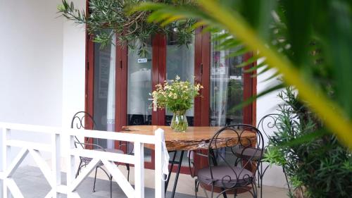 una mesa con sillas y un jarrón de flores en un porche en Vang Anh Homestay Hoi An en Hoi An