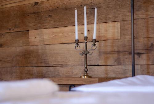 a candle holder on a wooden wall with three candles at Ethno Sazano Hotel in Sazano