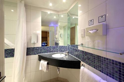 a bathroom with a sink and a mirror at Holiday Inn Express London - Newbury Park, an IHG Hotel in Ilford