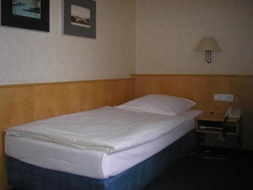 a bed in a hotel room with a phone next to it at AKZENT Hotel Altes Casino in Fulda
