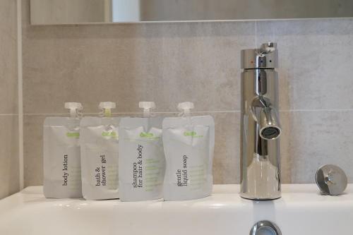 un grupo de cuatro botellas sentadas en el lavabo del baño en Floating vacationhome Tenerife, en Maastricht