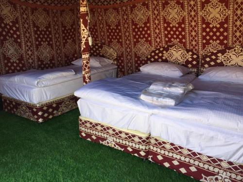 two beds in a room with green grass at Oman desert private camp in Shāhiq