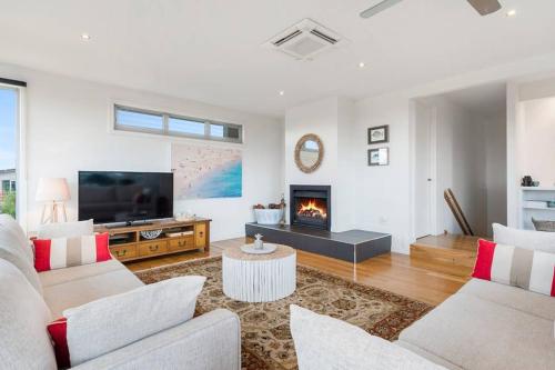 Una sala de estar con un sofá y una chimenea. en Aires Coastal Beach House Luxury with Ocean Views, en Aireys Inlet
