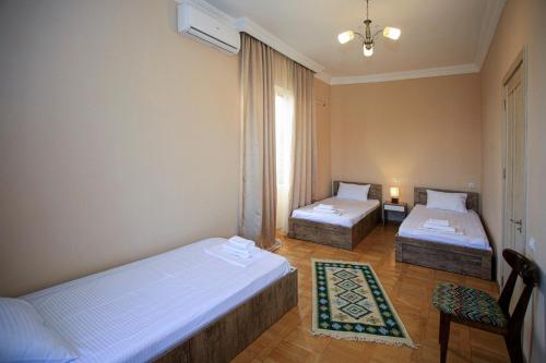 a room with two beds and a table and a chair at Bucha`s Guest House & Wine Cellar in Tʼelavi