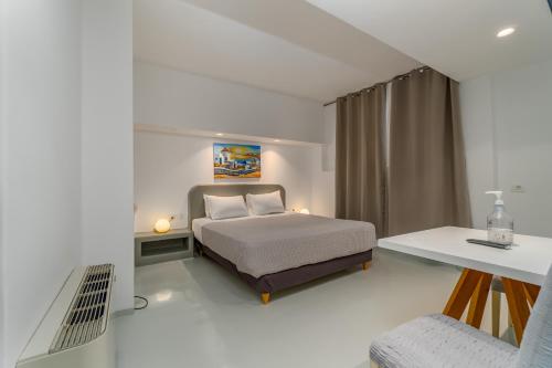 a white bedroom with a bed and a desk at Central Fira Suites in Fira