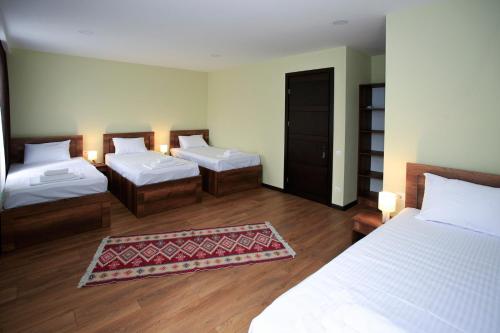 a hotel room with two beds and a rug at Bucha`s Guest House & Wine Cellar in Tʼelavi