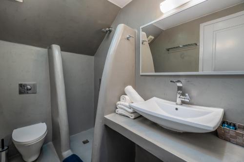 a bathroom with a sink and a toilet and a mirror at Central Fira Suites in Fira