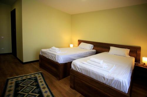 a bedroom with two beds with white sheets and a rug at Bucha`s Guest House & Wine Cellar in Tʼelavi