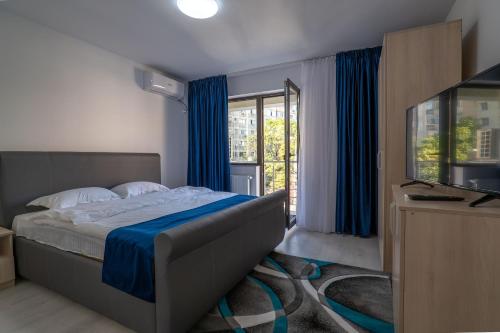 1 dormitorio con 1 cama con cortinas azules y TV en Hotel Simona en Bucarest