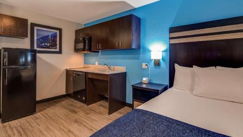 a hotel room with a bed and a desk and a kitchen at SureStay Plus Hotel by Best Western Humble in Humble
