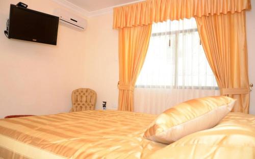 1 dormitorio con 1 cama, TV y ventana en Hotel Casa Del Rio Guayas en Guayaquil