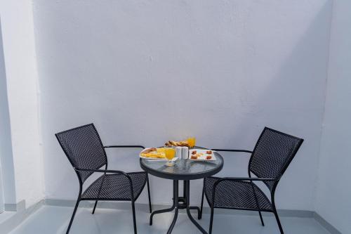 a table with three chairs and a plate of food on it at Central Fira Suites in Fira