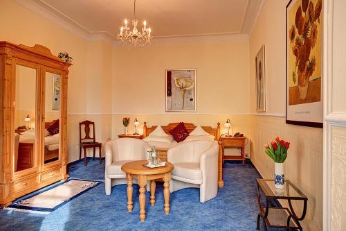 a living room with a couch and chairs and a table at Stadthotel Detmold in Detmold