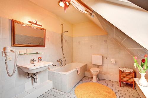 a bathroom with a sink and a tub and a toilet at Stadthotel Detmold in Detmold