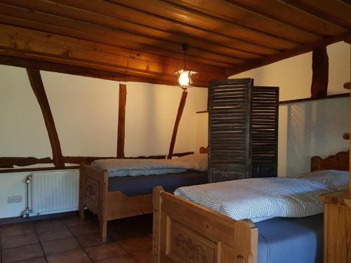 two beds in a room with wooden ceilings at Das Alte Kneipchen in Oberhambach