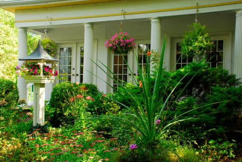 a white house with flowers in the front yard at Brockamour Manor Bed and Breakfast in Niagara on the Lake
