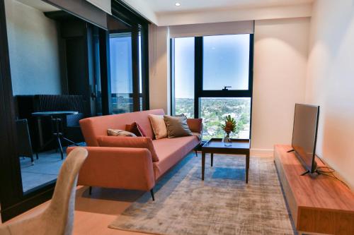 a living room with a couch and a tv at Box Hill Central Sky One Apartment in Box Hill