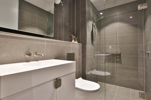 a bathroom with a toilet and a sink and a shower at Box Hill Central Sky One Apartment in Box Hill