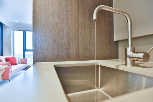 a kitchen with a stainless steel sink and a couch at Box Hill Central Sky One Apartment in Box Hill