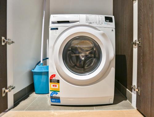 a washing machine in a room with a door open at Box Hill Central Sky One Apartment in Box Hill