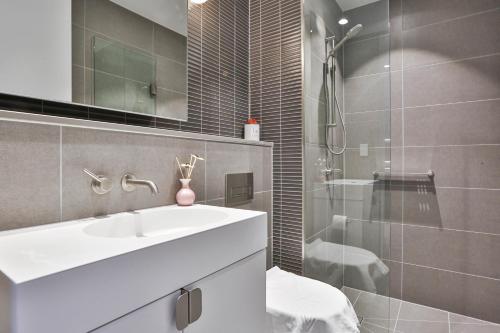 a bathroom with a white sink and a shower at Box Hill Central Sky One Apartment in Box Hill