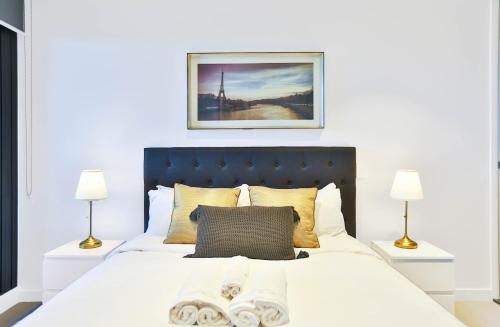 a bedroom with a large white bed with two lamps at Box Hill Central Sky One Apartment in Box Hill