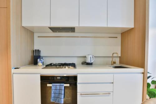 a kitchen with white cabinets and a stove top oven at Box Hill Central Sky One Apartment in Box Hill