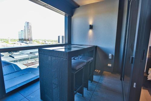 a room with a table and a window with a stool at Box Hill Central Sky One Apartment in Box Hill